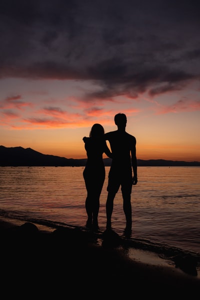 日落时在海滩上接吻的情侣剪影
